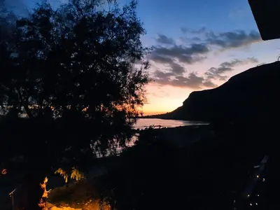 a sunset over a body of water with a tree at Georgoshouse Lykos beach Sfakia in Livanianá