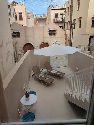 a balcony with a table and an umbrella and chairs at Casa De Potie in Chania Town