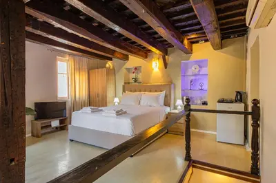 a bedroom with a white bed and a television at Ydragogeio Rooms Old Town in Chania Town