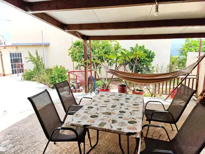 a table and chairs on a patio with a hammock at Village house with a nice garden in Stérnai