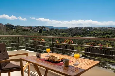 a table on a balcony with two glasses of orange juice at Luxury Apartment in Halepa in Chania Town