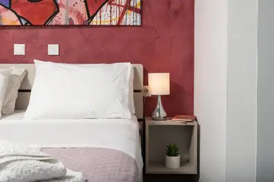 a bedroom with a white bed with a red wall at Luxury Apartment in Halepa in Chania Town