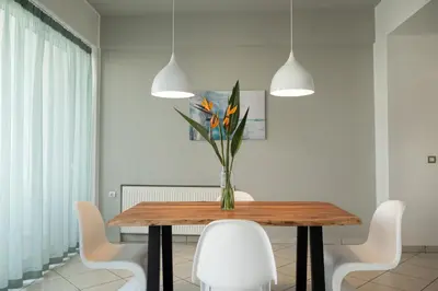 a dining room with a wooden table and white chairs at The Teacher's Home 2 minutes away from the beach in Galatás