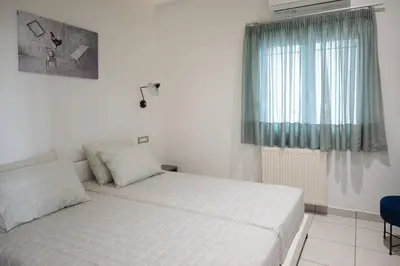 a white bedroom with a bed and a window at The Teacher's Home 2 minutes away from the beach in Galatás