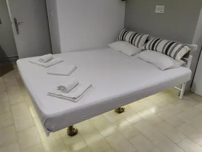 a large bed with white sheets and pillows on it at central cozy and lovely house in Chania Town