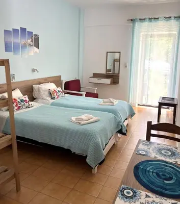 a bedroom with two beds and a chair at Milos Alexandra Studio in Frangokastello