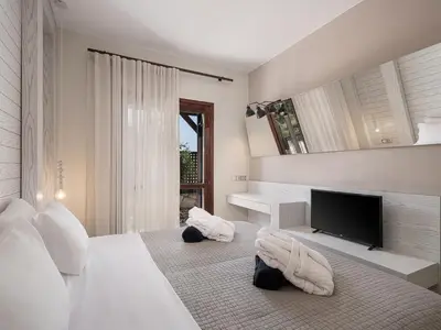 a bedroom with a bed with a television and towels at La Torre Villa in Palio Gerani