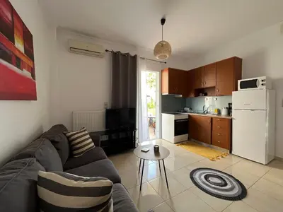 a living room with a couch and a kitchen at Seaside cozy apartment in Aghii Apostoli