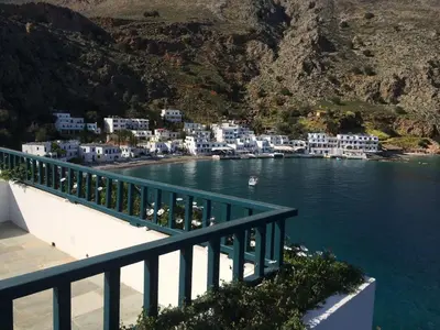 a view of a harbor with blue buildings and water at Hotel Porto Loutro on the Hill in Loutro