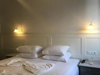 a bed with two pillows and two lights on it at Hotel Porto Loutro on the Hill in Loutro