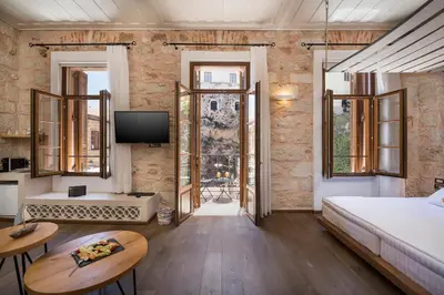 a bedroom with a bed and a tv and some windows at Ambassadors Residence Boutique Hotel in Chania Town