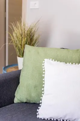 a white pillow sitting on a couch with plants at Fanouris Luxury Apartments in Chania Town