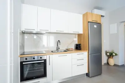 a kitchen with white cabinets and a stainless steel refrigerator at Fanouris Luxury Apartments 2 in Chania Town
