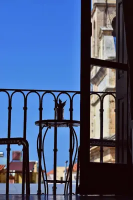 a table and chair on a balcony with a window at Cozy rooms at the old Venetian Harbor, Chania Town in Chania Town
