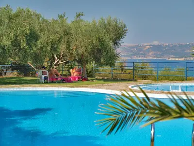 a blue swimming pool with a view of the water at Artemis Apartments in Kalyves