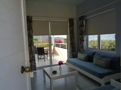 a living room with a blue couch and a balcony at Artemis Apartments in Kalyves
