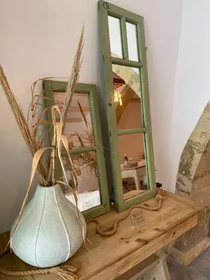 a mirror sitting on a table next to a vase at NiMa Maison in Kissamos