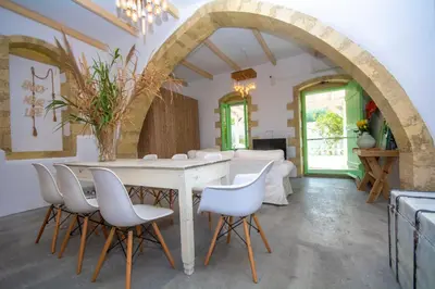 a dining room with a table and white chairs at NiMa Maison in Kissamos