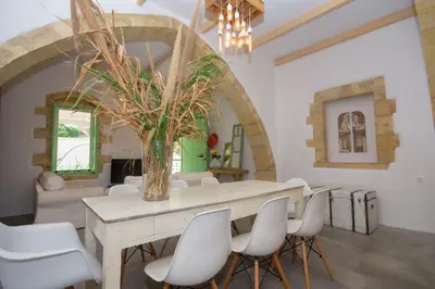 a dining room with a table and white chairs at NiMa Maison in Kissamos