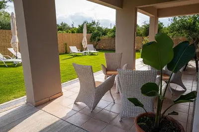 a patio with chairs and a potted plant at Meraki Cretan Hospitality in Maleme
