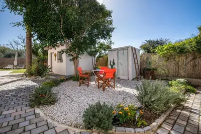 a patio with a table and chairs in a garden at Meraki Cretan Hospitality in Maleme