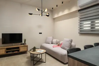 a living room with a white couch and a tv at Limani elegant apartments in Souda