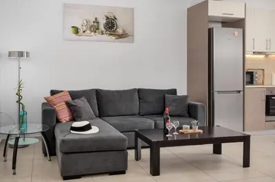 a living room with a gray couch and a table at 3 bedroom apt in Nea Chora 400 meters walk to the beach in Chania Town