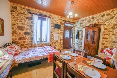 a living room with a table and a stone wall at Stone house for relaxation in Elos in Kissamos