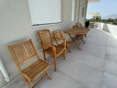 a porch with wooden chairs and a table on a balcony at Luxury Dream with Private Jacuzzi in Kaloudhianá