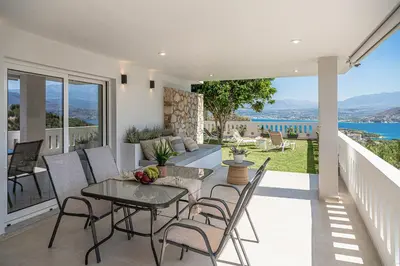 a patio with a table and chairs and a view of the ocean at Elysian Sea-View Chania in Stérnai