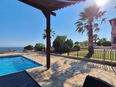 a swimming pool with a giraffe standing next to the ocean at Dreamy South Sea View Apartments with Pool in Frangokastello