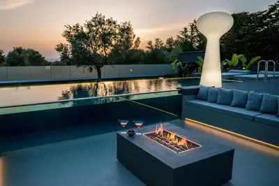 a living room with a fireplace next to a swimming pool at Chania lux villa with Heated pool in Chania Town