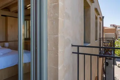 a room with a balcony with a bed and a window at Kallergon Luxury Suites in Chania Town