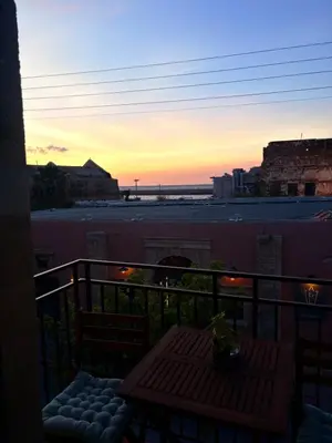 a sunset on a balcony with a table at Kallergon Luxury Suites in Chania Town