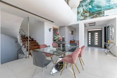 a dining room with a glass table and pink chairs at Crystal Waves lux villa-Homeleader in Chania Town