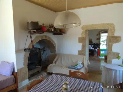 a living room with a white couch and a fireplace at Tsikalaria Traditional Stone House in Tsikalariá
