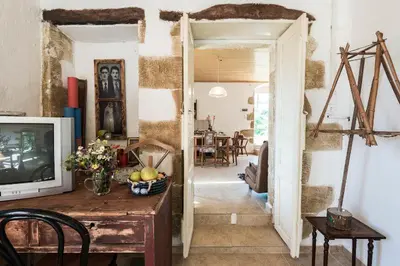 a living room with a television and a table with flowers at Tsikalaria Traditional Stone House in Tsikalariá
