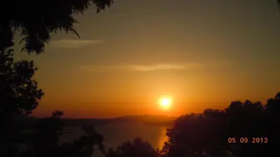 a sunset over a lake with the sun in the sky at Tsikalaria Traditional Stone House in Tsikalariá