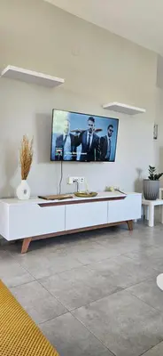 a white living room with a tv on the wall at heaven suite elafonisi in Elafonisi