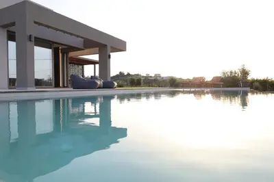 a swimming pool in front of a building with water at ISKIOS Premium in Agia Marina Nea Kydonias