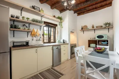 a kitchen with white cabinets and a table and chairs at Joel Living Collection - Rustic Villa in Áptera