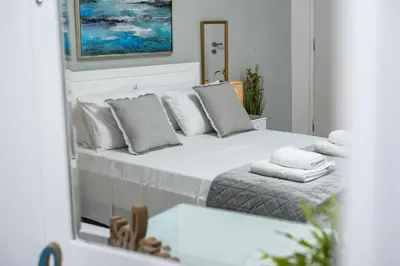 a bedroom with a large white bed and a mirror at ''Meraviglia'' casa ''Nefeli'' in Chania Town