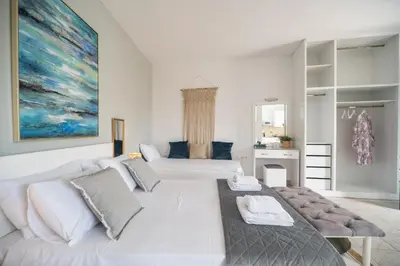 a white bedroom with a large bed and a kitchen at ''Meraviglia'' casa ''Nefeli'' in Chania Town