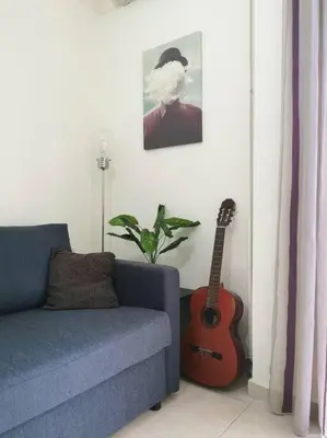 a living room with a blue couch and a guitar at Comfy APT in Chania City Center in Chania Town