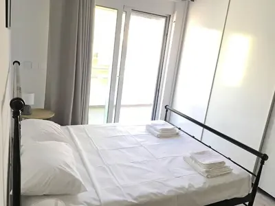 a bedroom with a white bed with a large window at Pegasus Amazing Flat, 1,5min Walk To The Beach in Chania Town