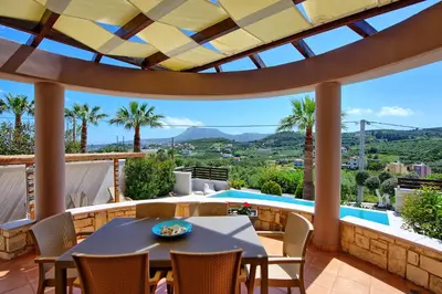 a patio with a table and chairs and a swimming pool at Villa Kostantina by PosarelliVillas in Plaka