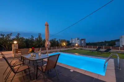 a patio with a table and chairs next to a swimming pool at Lithina charm villa with private pool and sea view in Kamisianá