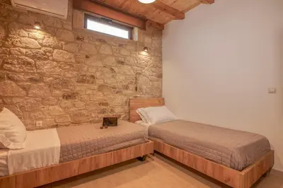 two beds in a room with a stone wall at Lithina charm villa with private pool and sea view in Kamisianá