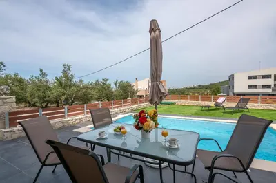 a table with flowers and an umbrella next to a pool at Lithina charm villa with private pool and sea view in Kamisianá