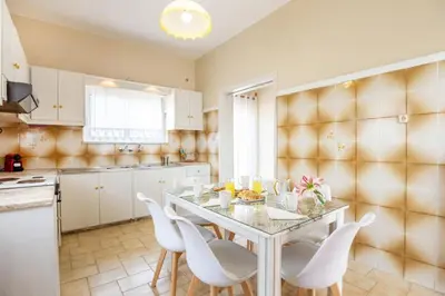 a kitchen with a white table and white chairs at Ortansia House near the Sea in Ayiá